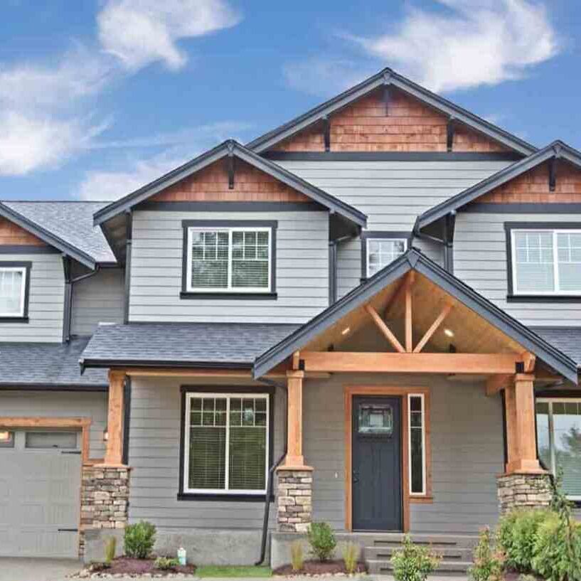 A grey house with gable roof and black trim and white framed windows 