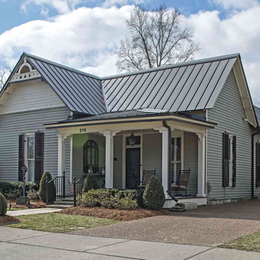 Grey house with black roof and white pillars and celling light above the wall