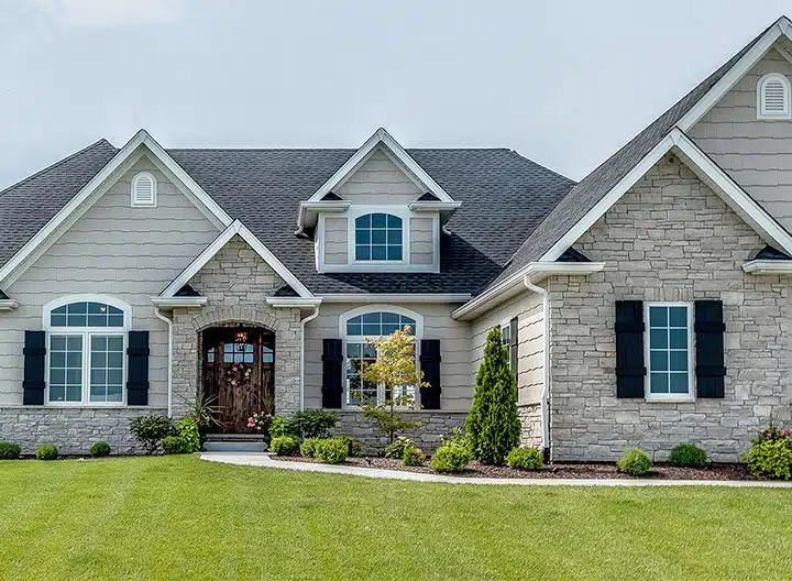 A light grey house with white trim and glass windows and garden outside of the house 
