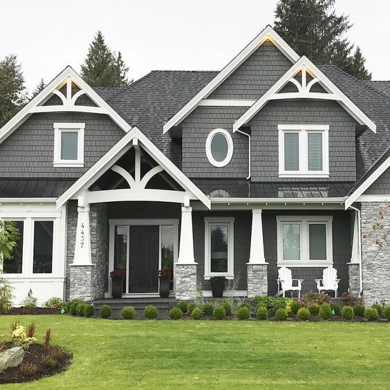Grey house with gable roof and white trim and windows and garden outside of the door