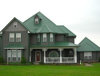 Grey house with green roof and white trim windows and garden outside of the house