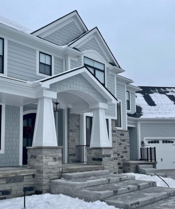 Grey house with white trim and stone base pillars