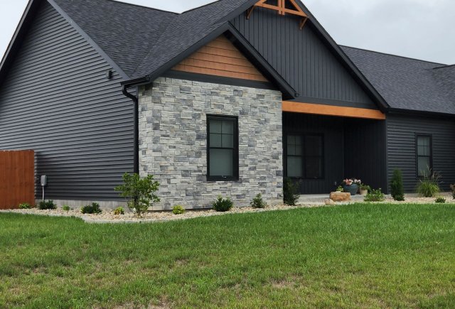 Grey house with stone and wooden accents and garden outside of the house