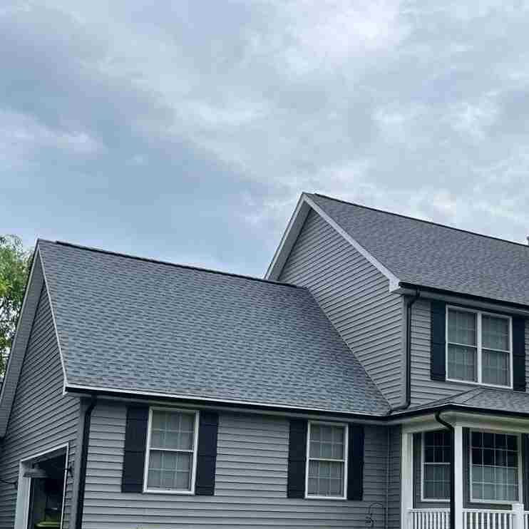 Grey hose with lack gutter and shutters and white trim windows 