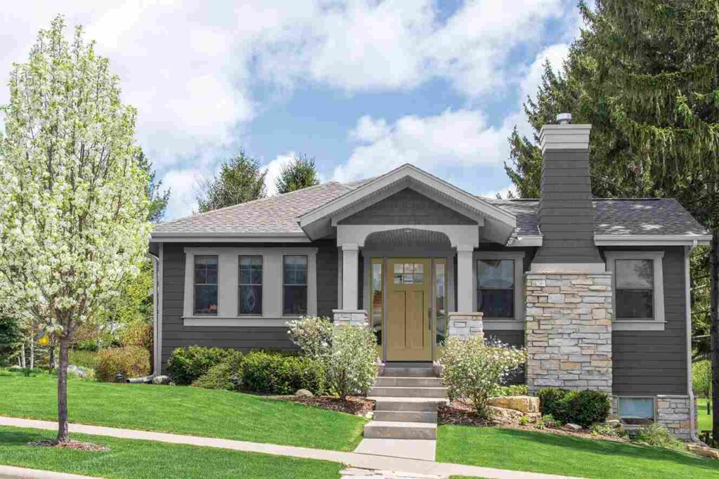 Grey house with white pillar and white framed windows and garden outside of the house