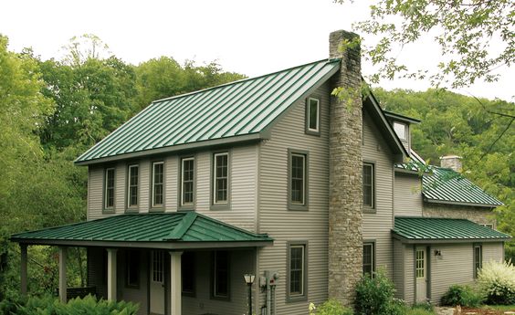 A light green house dark green roof and trim windows