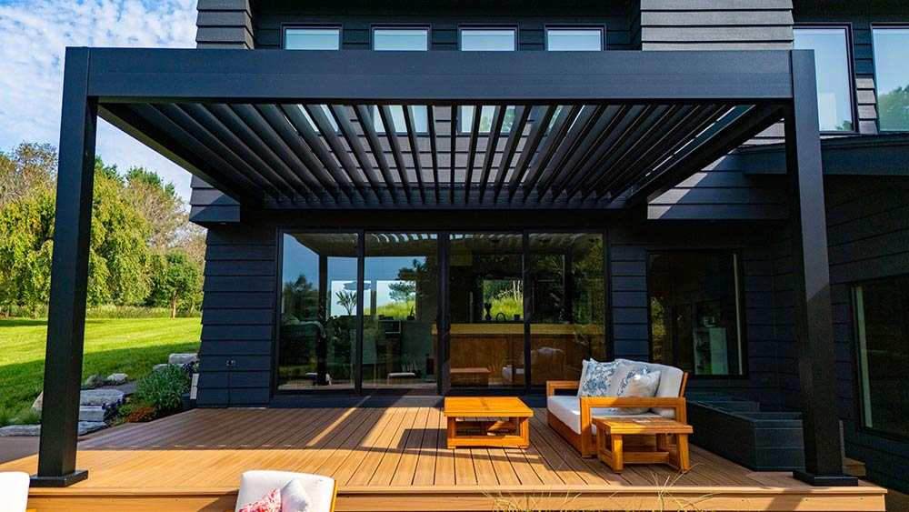 Black pergola on grey house with wooden decking