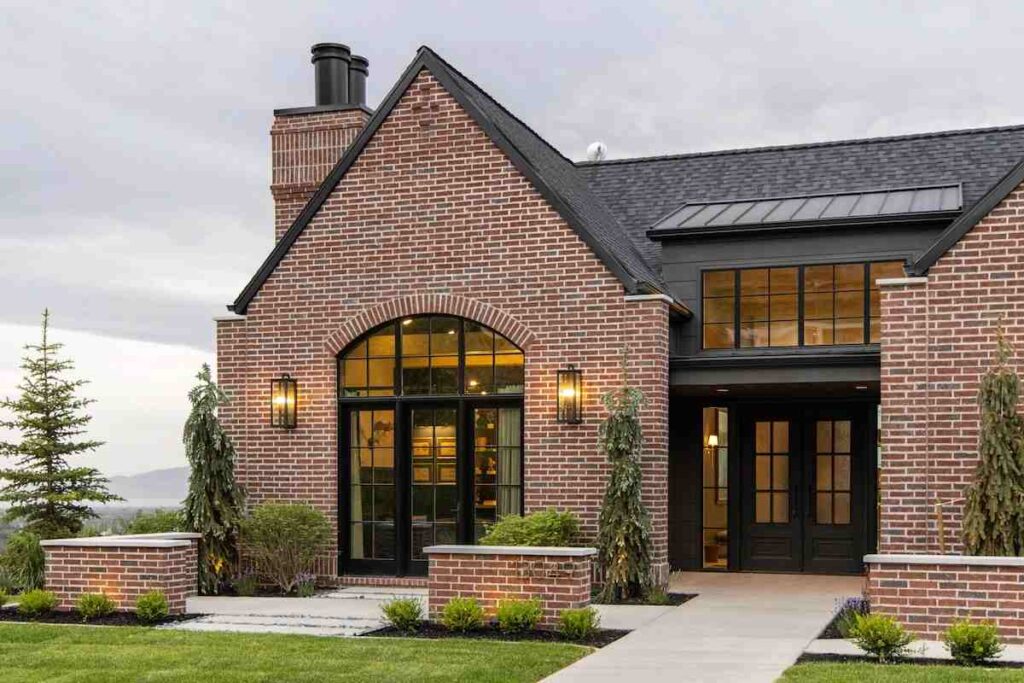 Red brick house with black roof and light on the wall