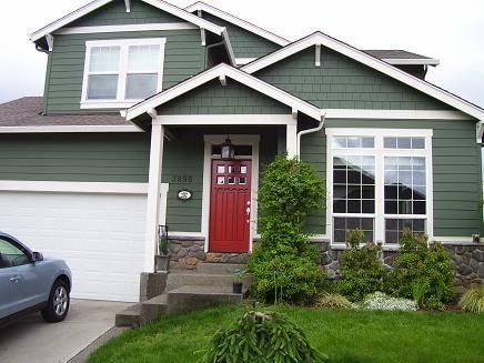 Green house with red door and garden outside of the house