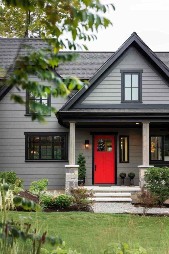Red front door and celling light on the wall and black trim window and garden outside of the door