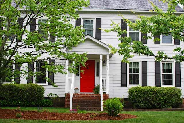 White house with black shutter and black front door and whit pillars 