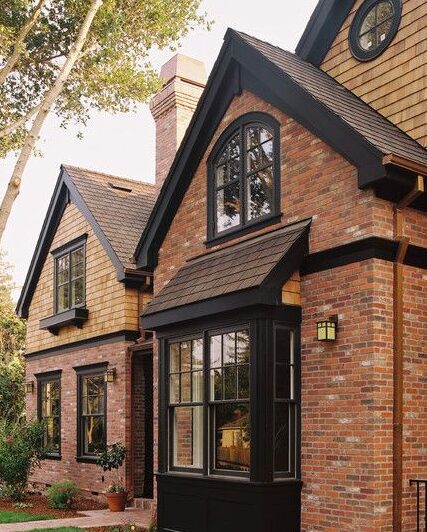 Red brick house with black trim and black framed windows and celling light on the wall