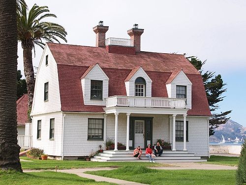 Red roof on white house and garden outside of the house and white balcony 