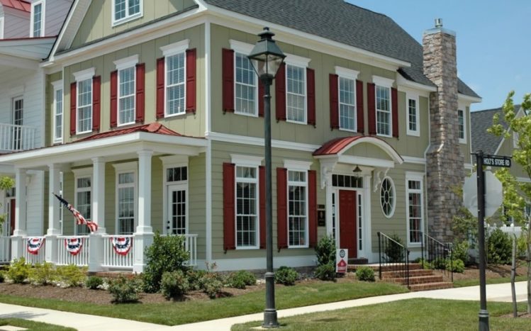 red shutter on green house and white trim windows and white pillar and red front door