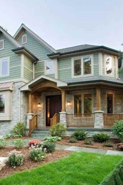 Two story sage green house with wood accents and white trim windows