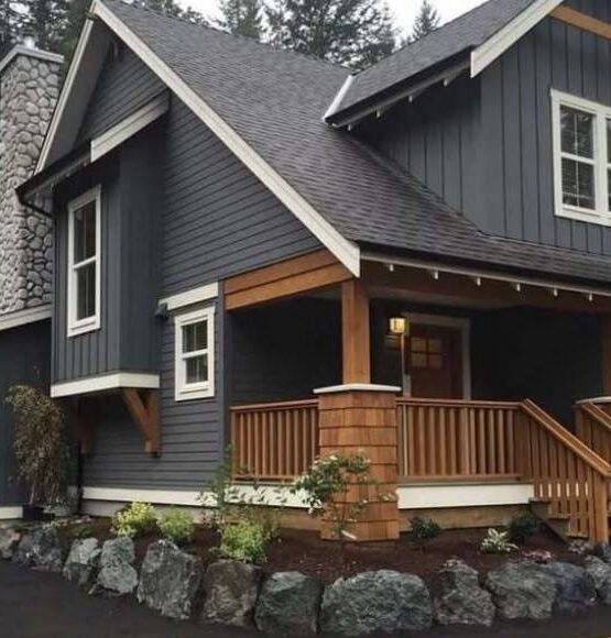 A stone pillar and wooden accents and white trim window and some stone outside of the door 