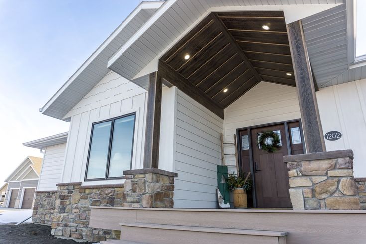 A white house with brown trim and stone cladding