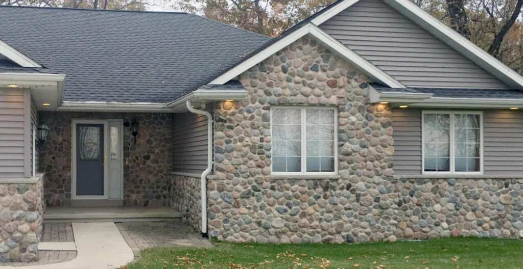Natural stone on grey house and white trim windows and grey front door