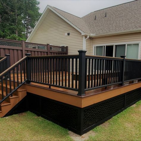 A tan house with black railing and wooden porch