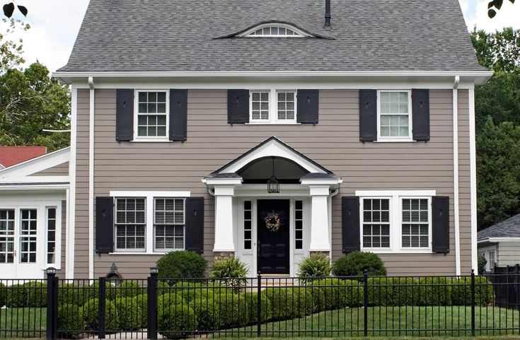 A tan house with black fencing around the house