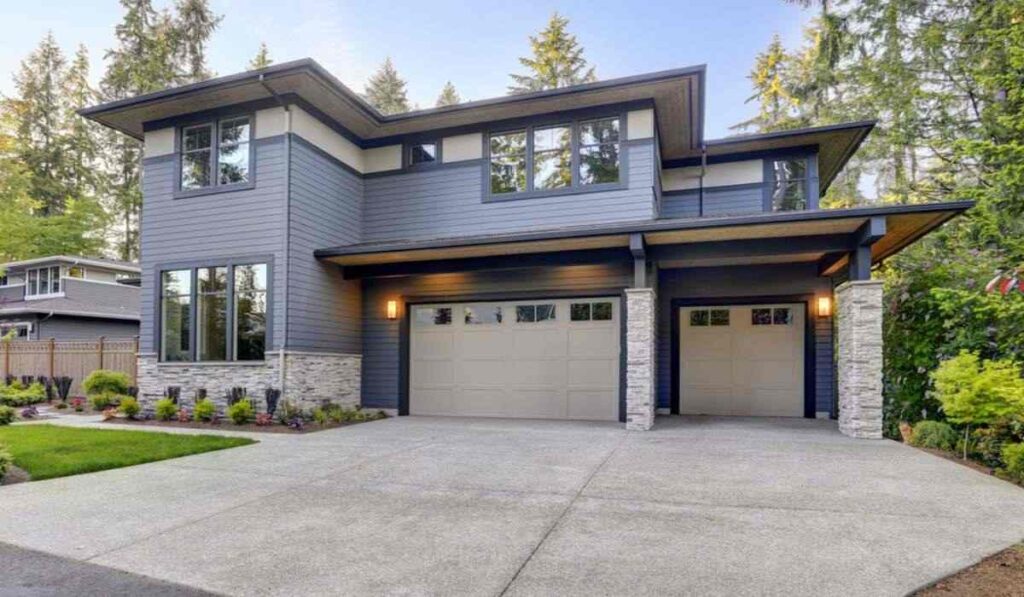 Grey house with black trim and warm lights above on the wall