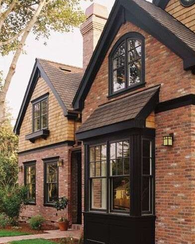 Red brick house with black scones lights on the wall and black framed windows