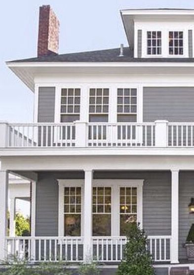 A grey house with white trim balcony and windows