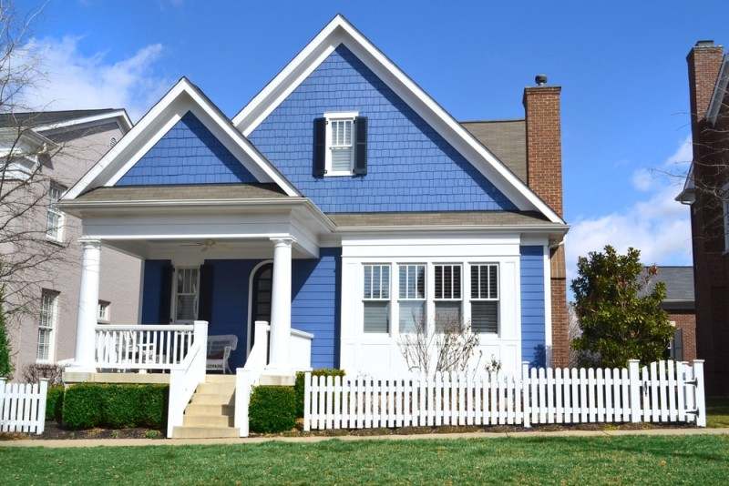 white fencing on blue house and white trim and garden outside of the house