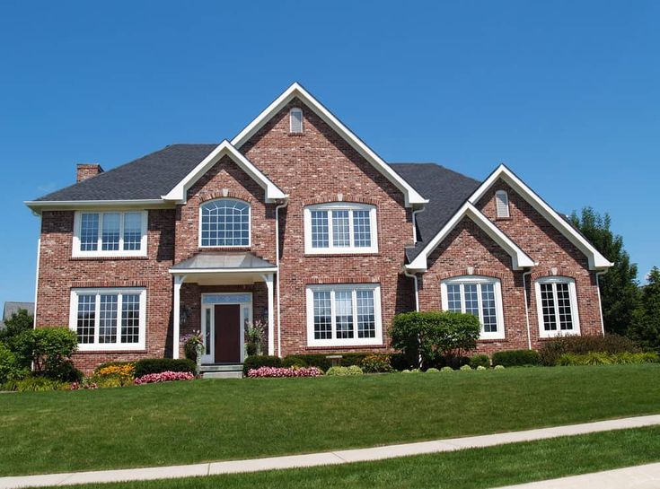 Red brick house with white trim window and garden outside of the house