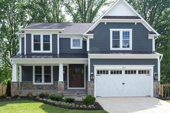 A blue house with white garage and wooden door