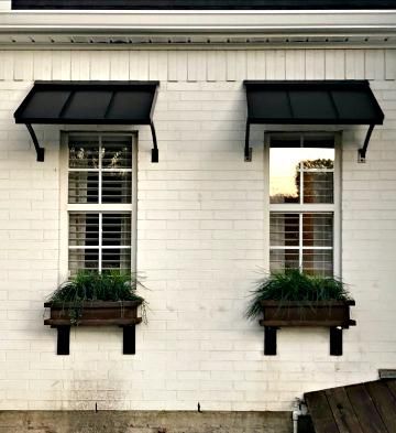 White house with black awnings and white framed windows