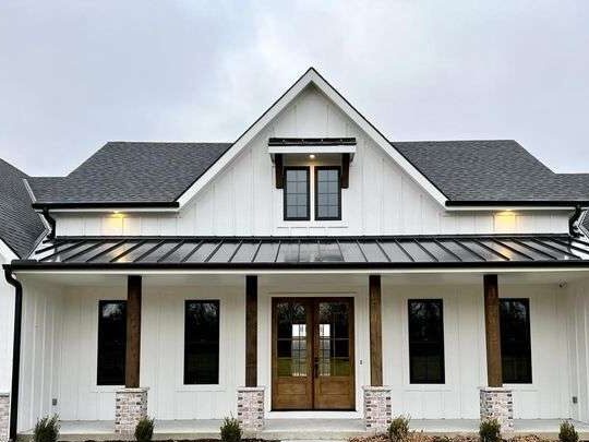 A white house with black windows and wooden pillars