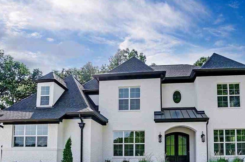 A white house with black roof and windows and lights on the wall 