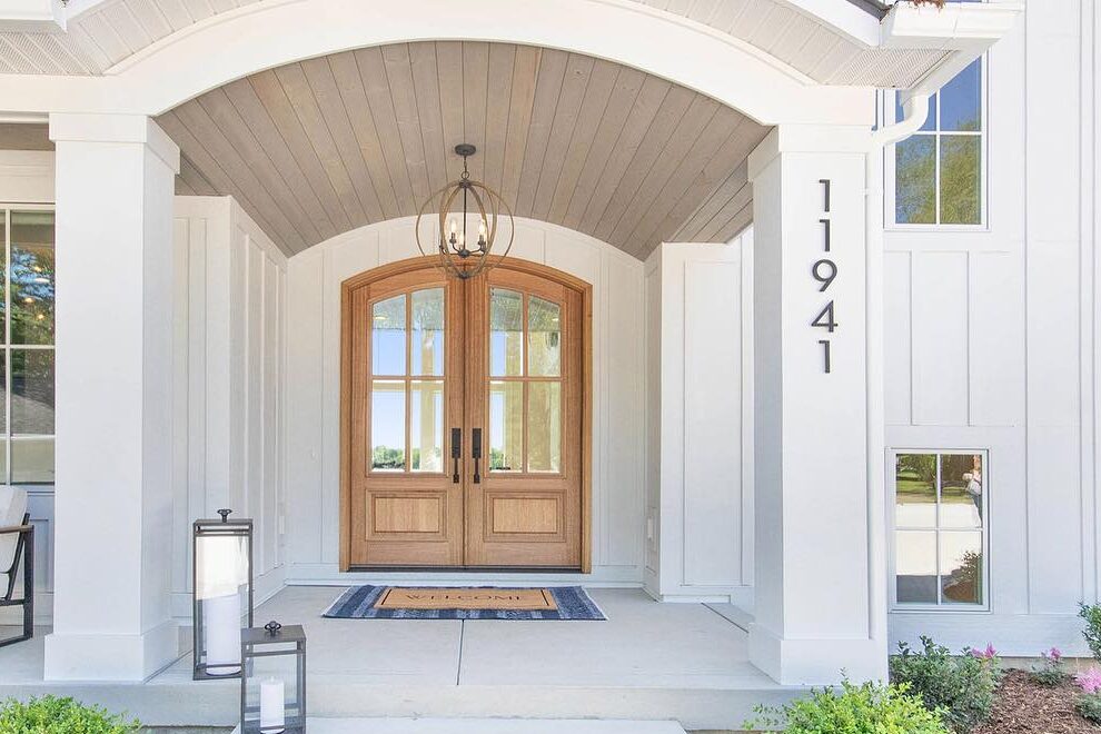 Wooden door on white house and black house number on the wall