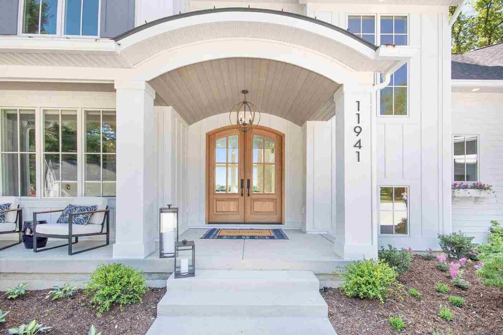White house with wooden door lamp above the wall.