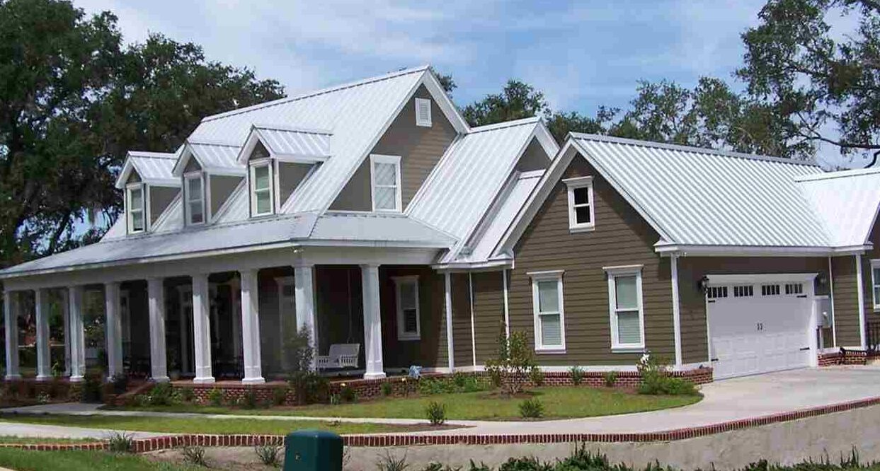Tan house with white roof and white trim windows and garden outside of the house