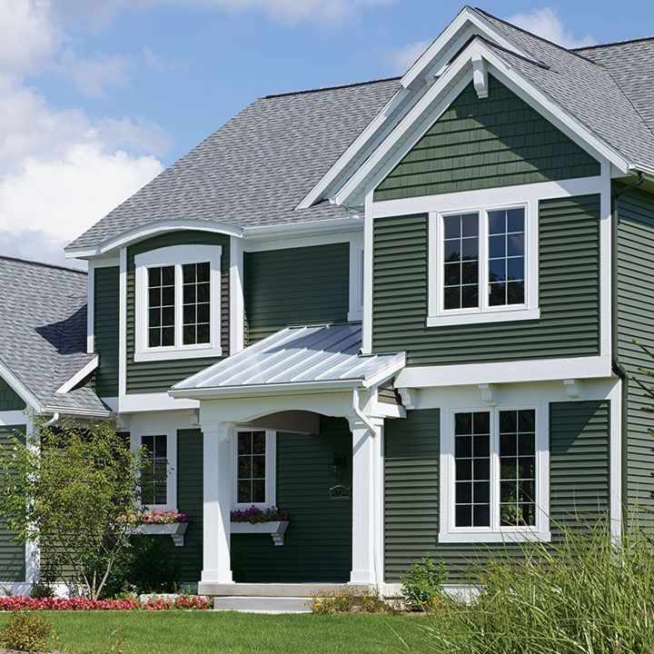 Green house with white windows and garden outside of the house