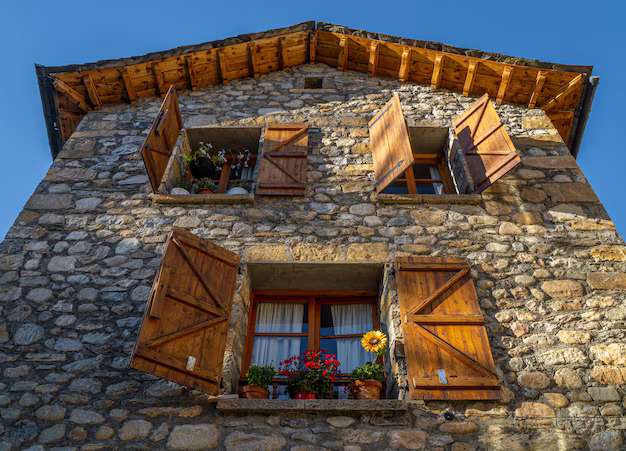Stone house with wooden shutters and windows and flowers 