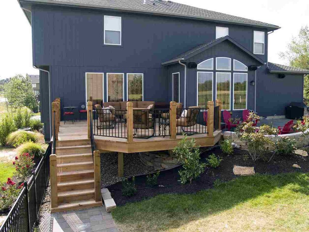 Dark blue house with wooden balcony and garden outside of the house