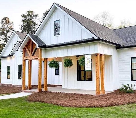 A white house with black trim and wooden pillar and glass windows 
