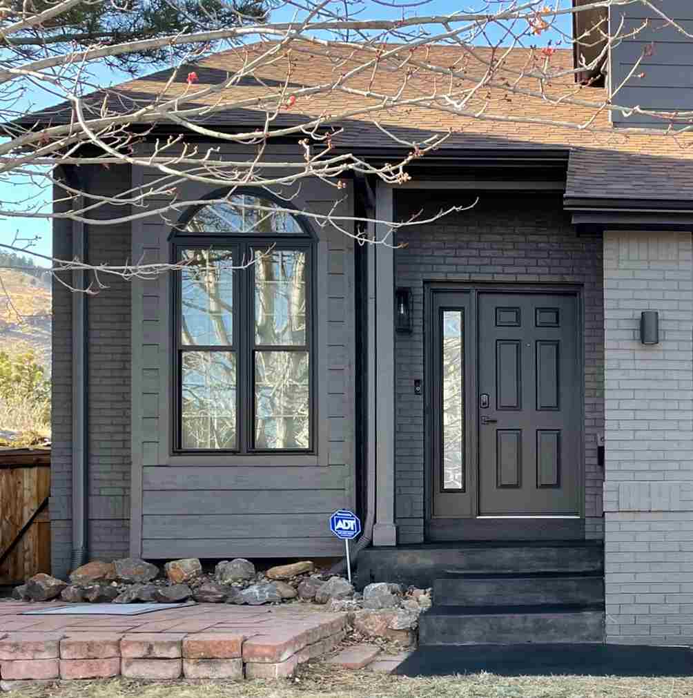 A grey house with black door and glass windows 