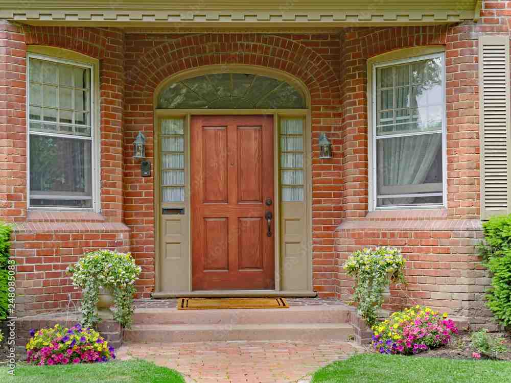 Wooden door on red. brick house and flowers outside of the house