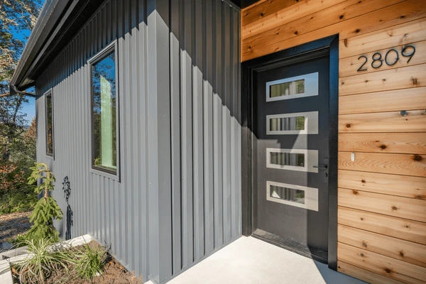 Wooden panel on grey house and black door