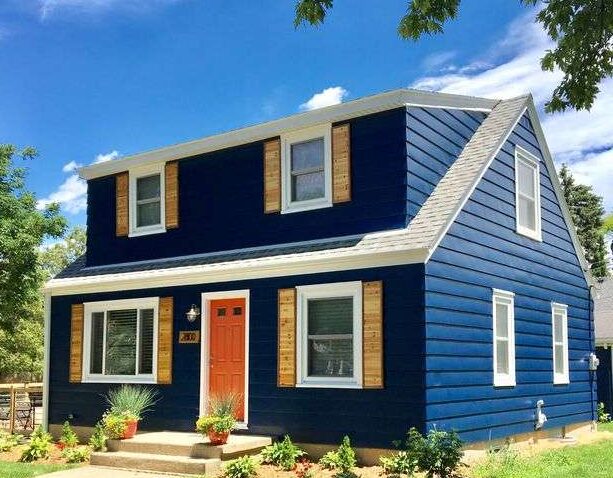 Wooden shutter on blue house with white trim and red door