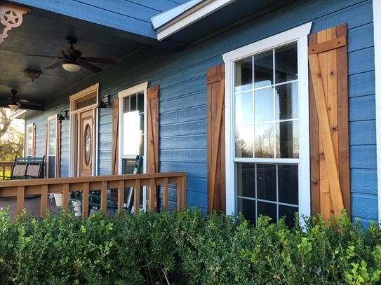 A blue house with wooden shutter and white trim windows
