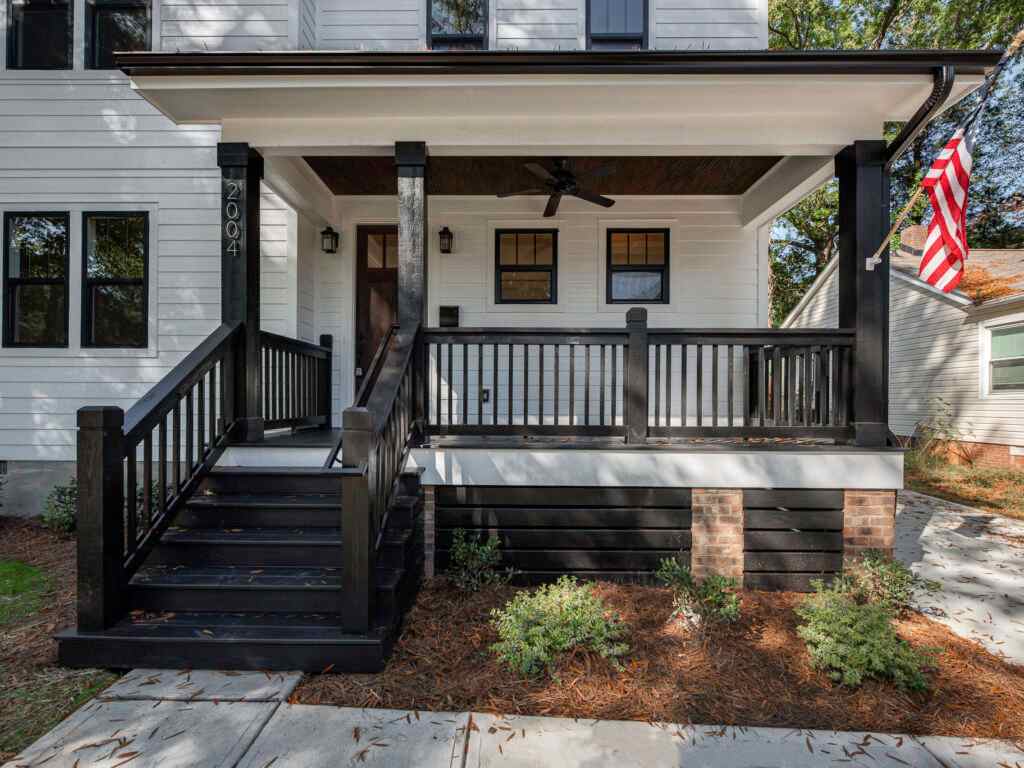 A white house with black framed windows and stair and black railing