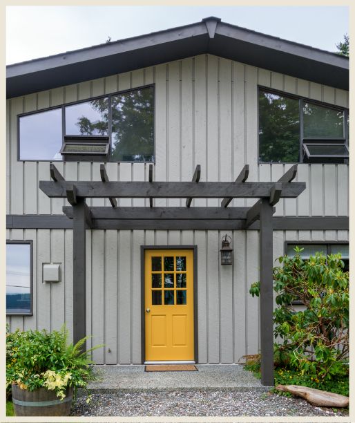 Grey house with yellow front door and black framed window