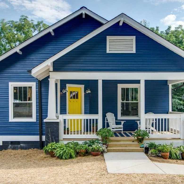 Blue house with yellow door and white chair outside of the door
