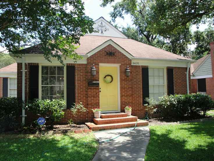 Yellow front door on red brick house and lamp above the wall with white trim