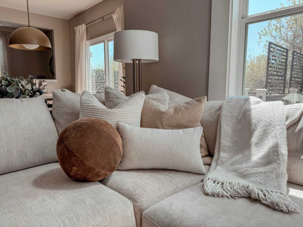 A living room with sofa and throw on sofa with cushions